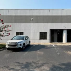 A front view of a building. A white SUV is parked in front of the building.