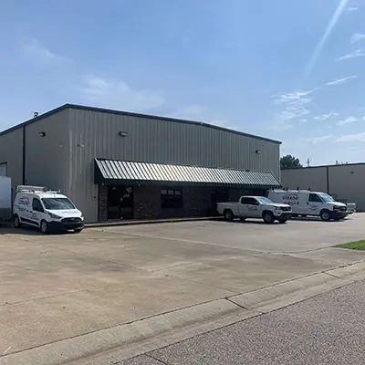 A side view of a Birmingham electrical warehouse building. Pickup trucks and delivery vehicles are parked in front of the building.